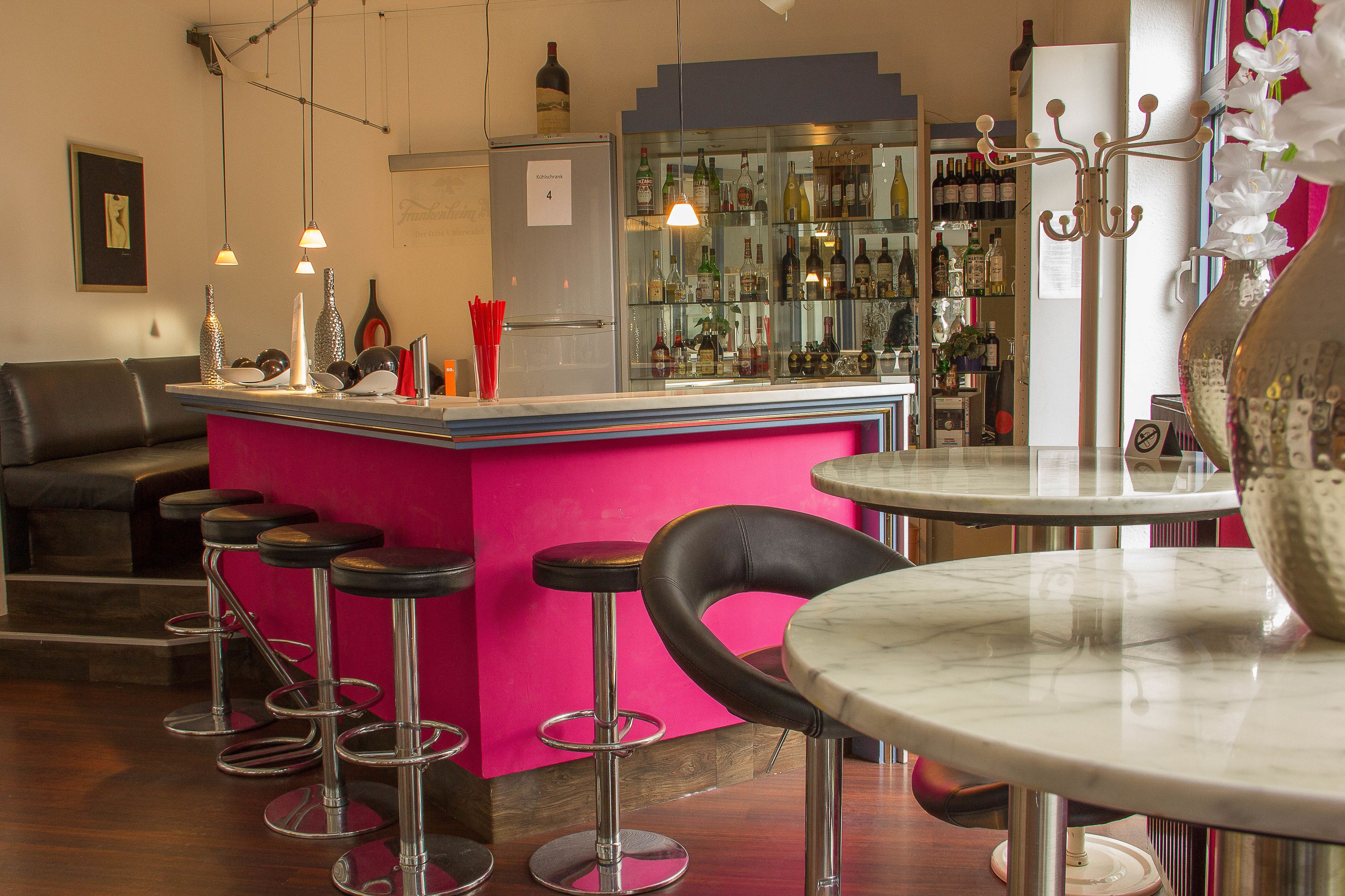 A bar area with stools, a counter, and a refrigerator.