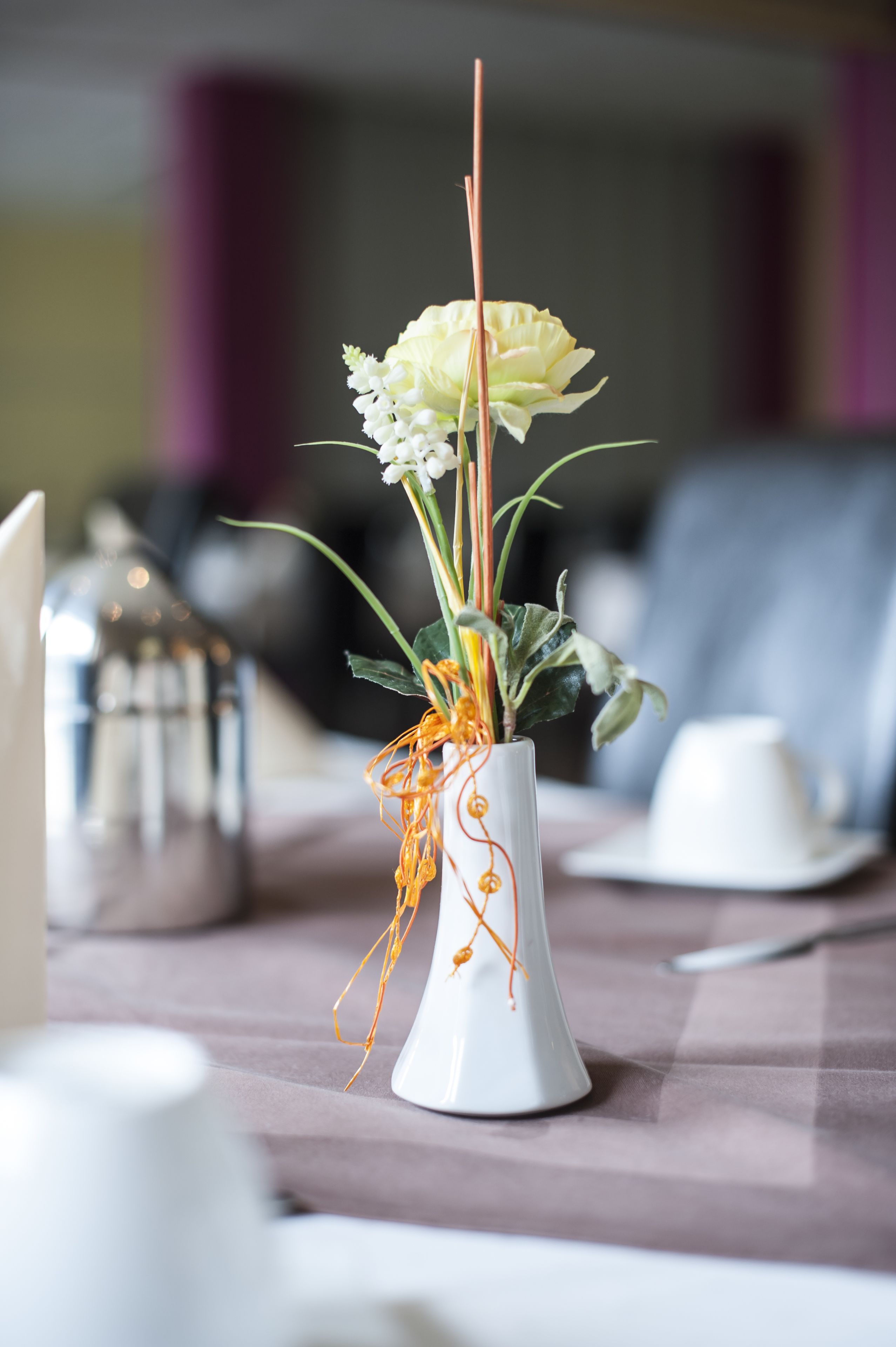 Una mesa con un jarrón blanco lleno de flores y adornos decorativos.