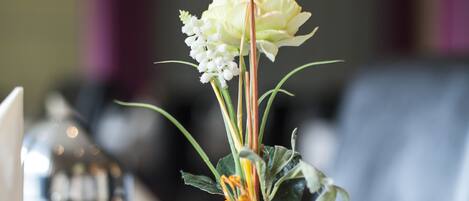 Una mesa con un jarrón blanco lleno de flores y adornos decorativos.