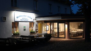 A hotel and restaurant with outdoor seating and a visible dining area inside. - Hotel Radduscher Hafen (Vetschau/Spreewald)