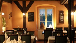 A restaurant interior with tables set for dining, a window with a view, and a sign on the wall. - Hotel Radduscher Hafen (Vetschau/Spreewald)