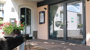 A hotel entrance with a glass door, a sign indicating it is a restaurant and hotel, and a flower planter outside. - Hotel Radduscher Hafen (Vetschau/Spreewald)