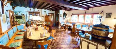 Ein traditionelles Gasthaus mit Holzboden, einem Gemeinschaftsraum mit Bänken und Tischen sowie einer Küchenzeile mit einem Fass auf der Arbeitsfläche.