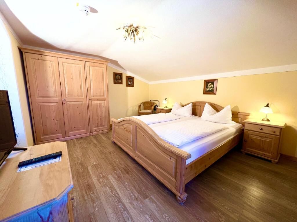 A bedroom with a wooden bed, a nightstand, a desk, and a wardrobe.