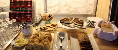 A buffet table with various food items, including desserts, cookies, and a selection of beverages.