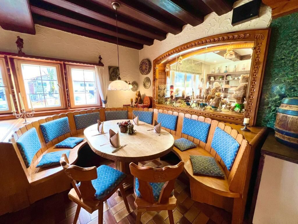 A cozy dining area with a round table, wooden chairs, and blue cushioned benches.