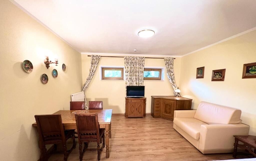 A living room with a dining table, chairs, a sofa, a TV, and a cabinet.