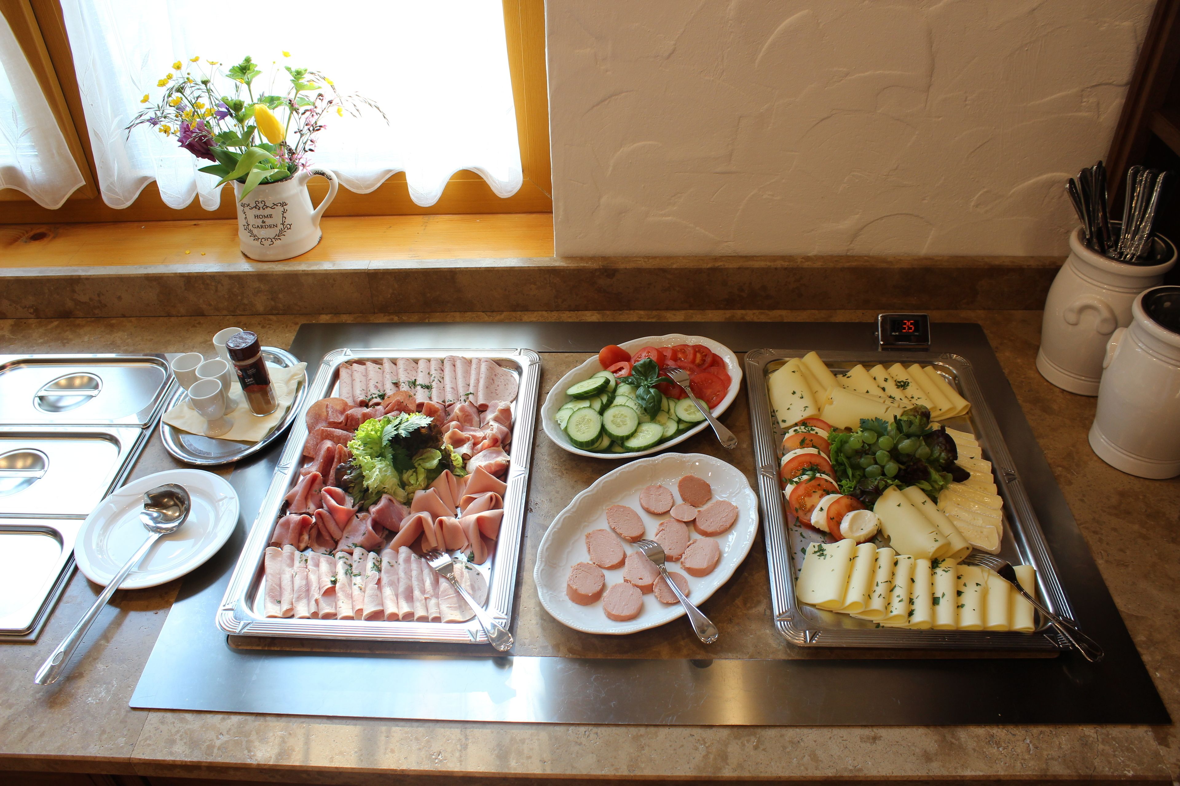 A buffet table with various food items including meats, cheeses, and vegetables.