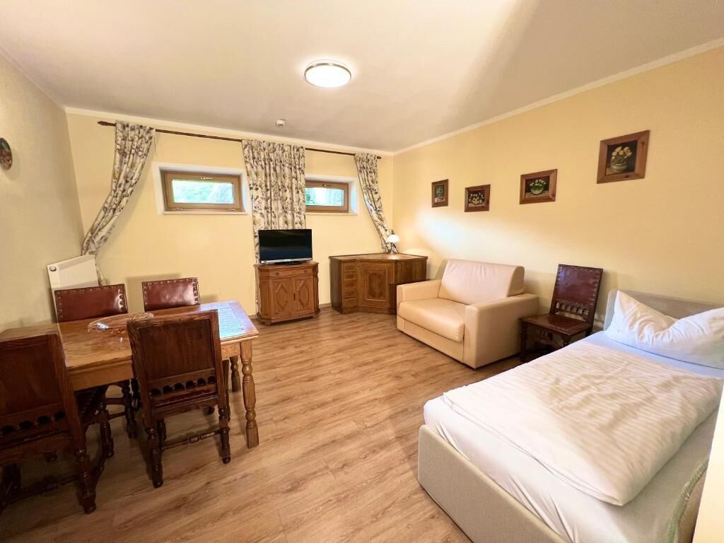 Une pièce comprenant un lit, un téléviseur, un bureau avec des chaises, un canapé et un petit meuble.