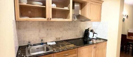 A kitchen with wooden cabinets, a black countertop, and a stainless steel sink.