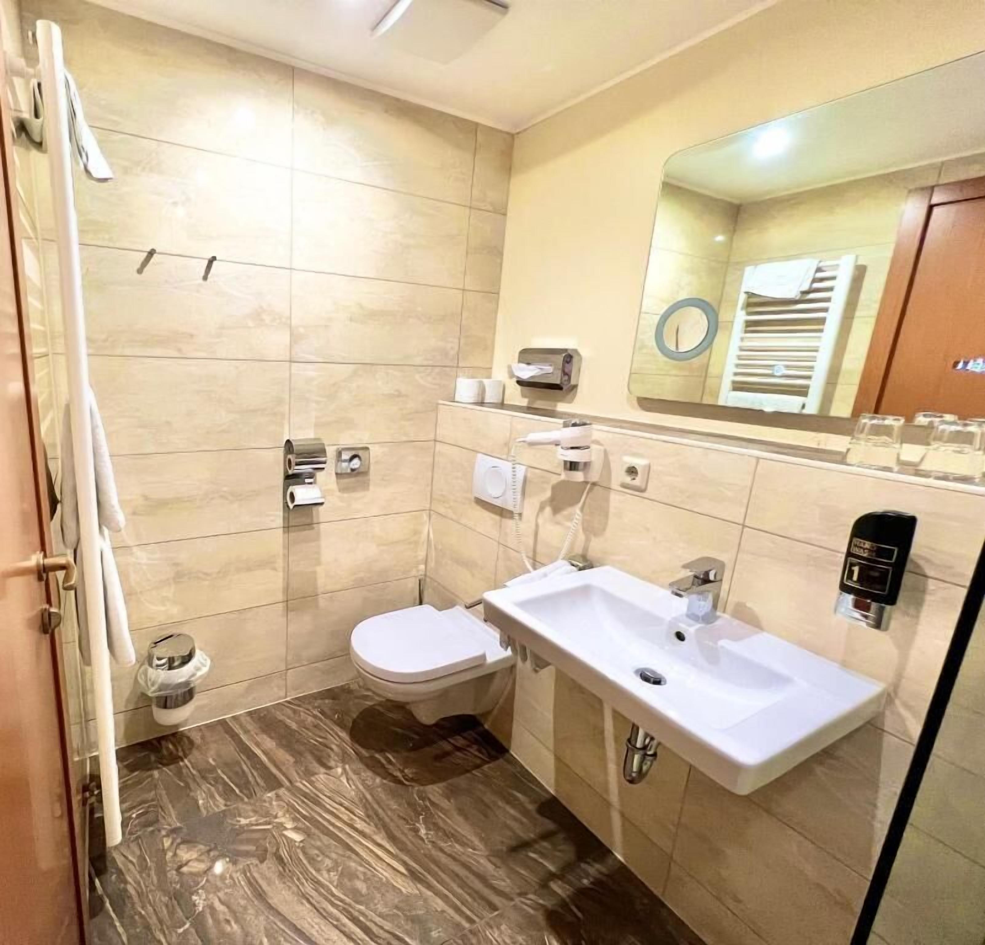 A modern bathroom with a toilet, sink, and mirror.