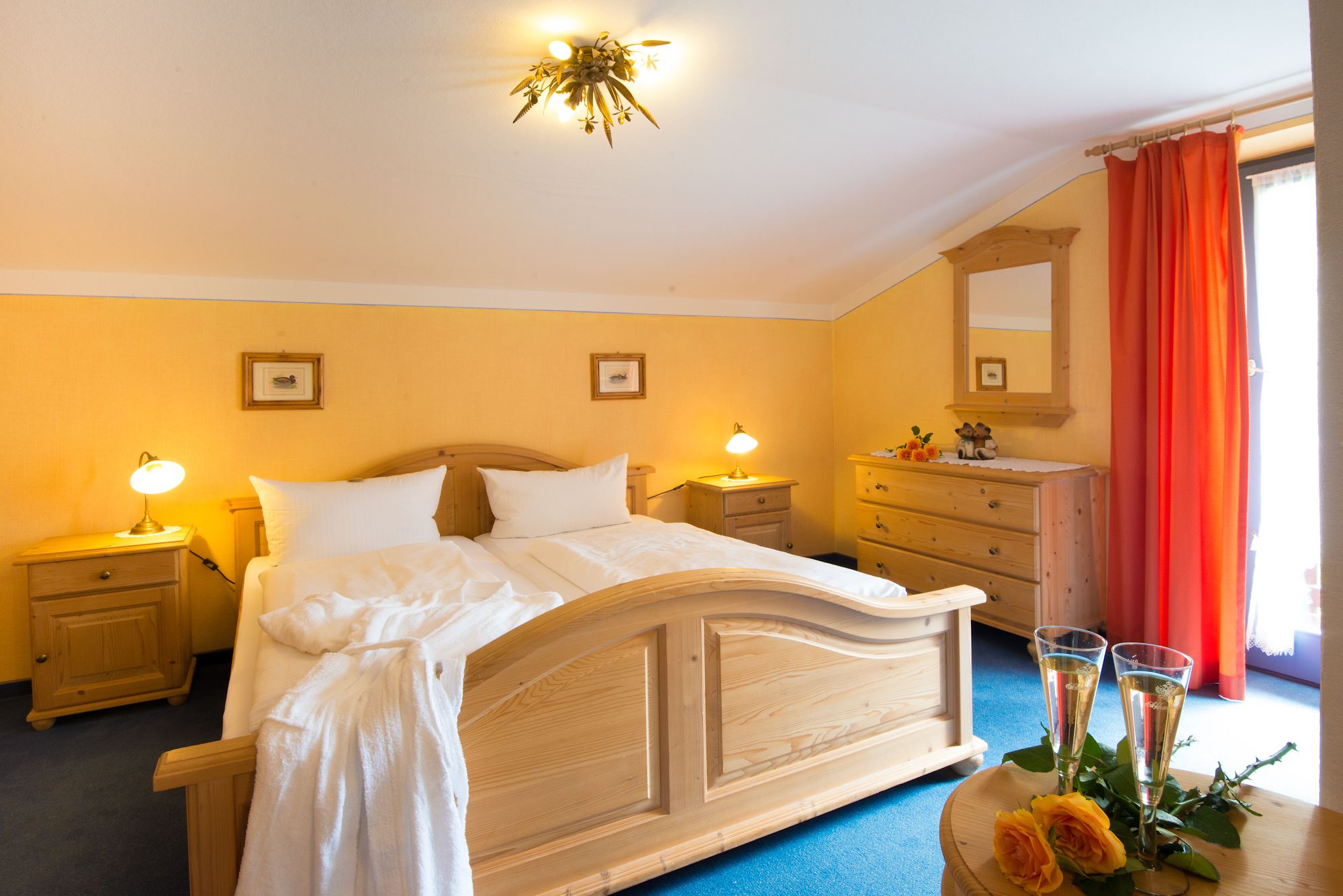 Una habitación de hotel con una cama de madera, dos lámparas de noche, un aparador y un espejo.