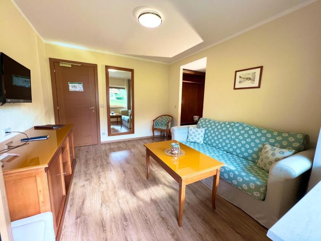Un salon avec un canapé, une table en bois et un téléviseur fixé au mur.