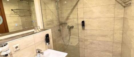 A modern bathroom with a glass-enclosed shower, a white sink, and a mirror.