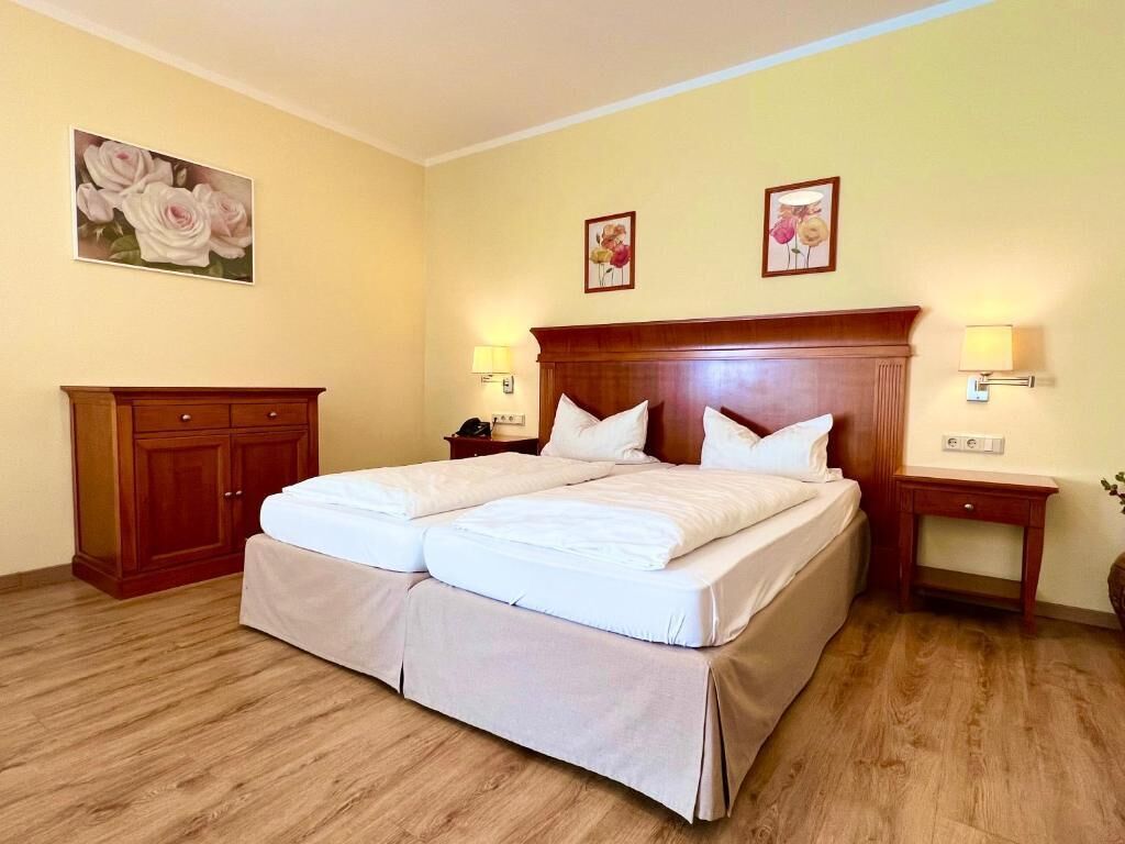 A double bed with a wooden headboard, two bedside tables with lamps, and a wooden wardrobe.