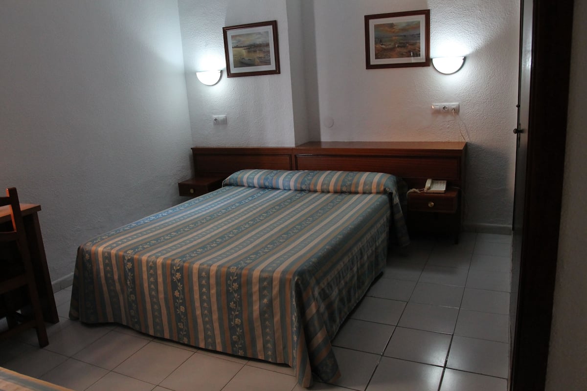 Un dormitorio con cama, mesitas de noche y un velador.