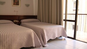 A hotel room with two beds, a painting on the wall, and a view of the outside through a large window. - Pensión Terminal (Málaga)
