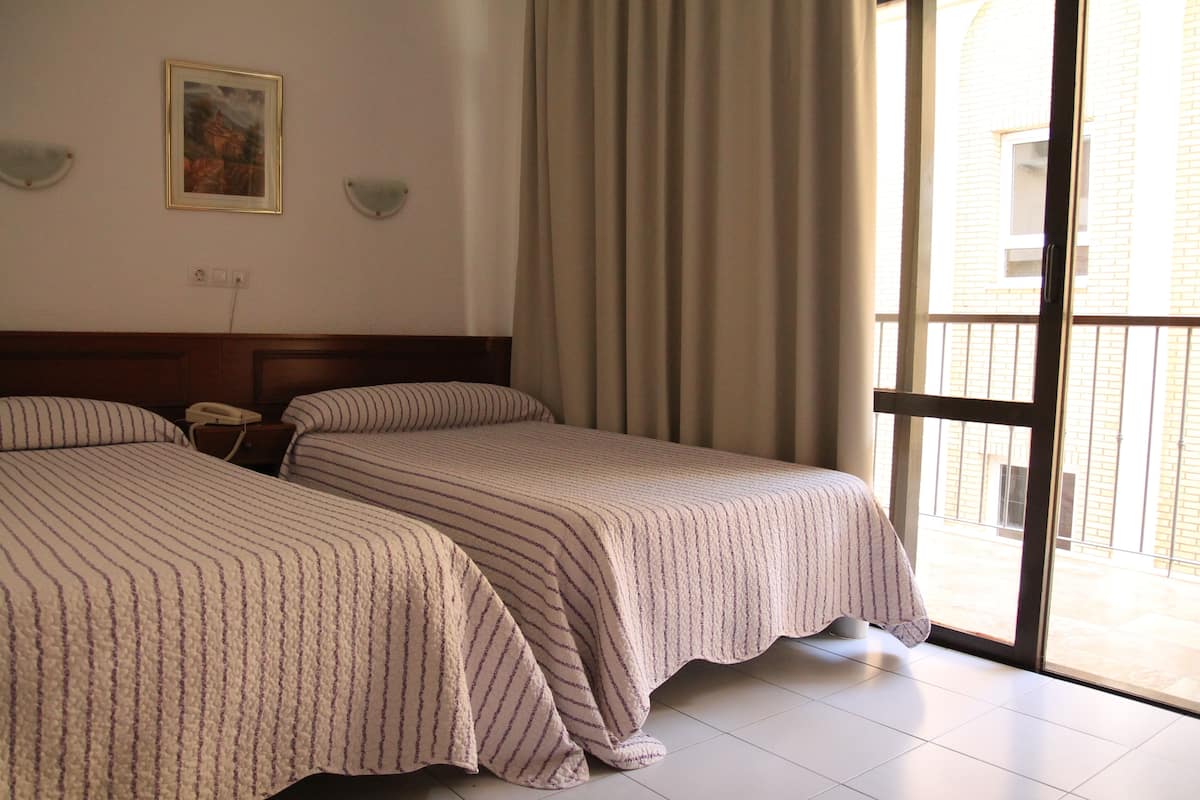 Habitación de hotel con dos camas, un cuadro en la pared y vistas al exterior a través de un ventanal grande.