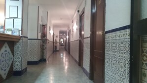 A hallway with patterned walls and a wooden door on the right. - Pensión Terminal (Málaga)