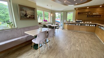 A modern kitchen with a wooden countertop, a dining area with a bench and chairs, and large windows offering a view of the outdoors.