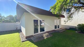 A small, single-story house with a sloped roof, a front door, and a sliding glass door. - Hotel Pension Kühne (Boltenhagen)