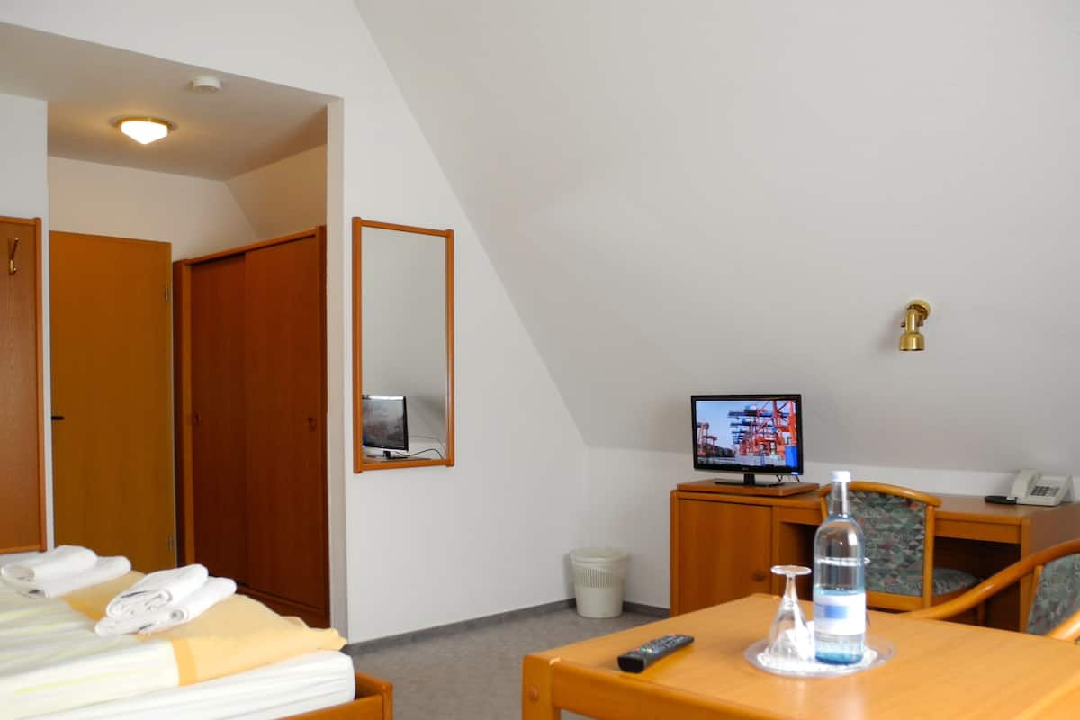 Una habitación de hotel con una cama, un escritorio con computadora, un televisor y una silla.