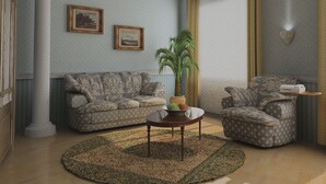 A living room with a patterned sofa, a round coffee table, and a potted plant. - Hotel Alfa (Neu-Isenburg)