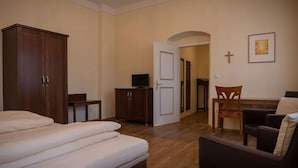 Ein Zimmer mit einem Bett, einem Schreibtisch, einem Sessel, einem Fernseher und einem Kleiderschrank.