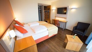 Una habitación de hotel con cama, escritorio, silla y televisión.