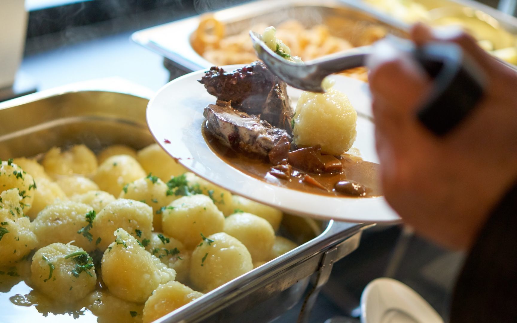 A buffet with various dishes including meat and potatoes.