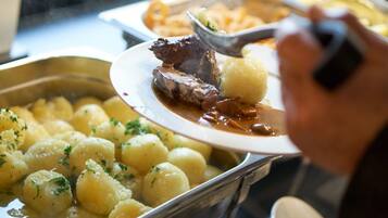 A buffet with various dishes including meat and potatoes.