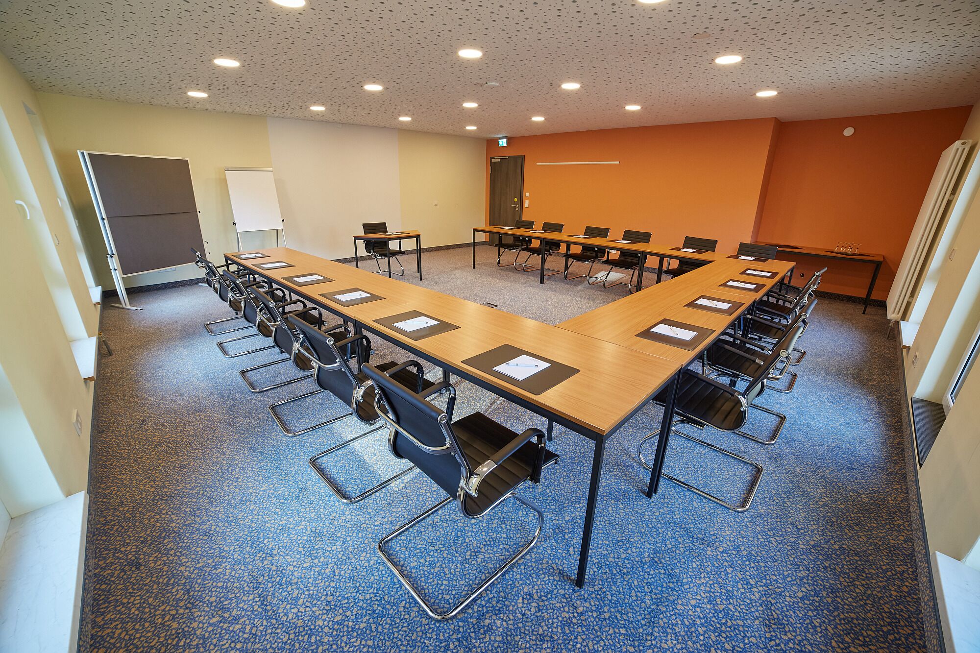 Ein Konferenzraum mit einem langen Tisch, Stühlen und einer Whiteboard-Tafel.