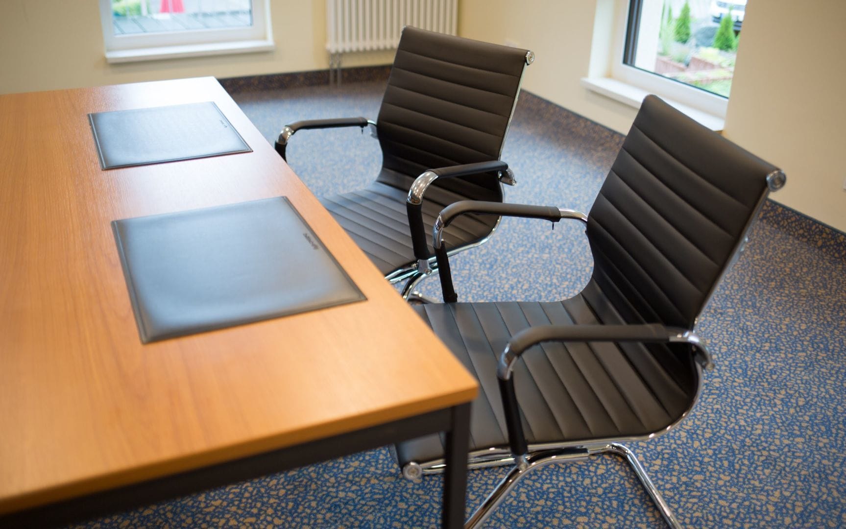 A conference room with a wooden table and four black office chairs.