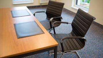 Una sala de conferencias con una mesa de madera y cuatro sillas de oficina negras.