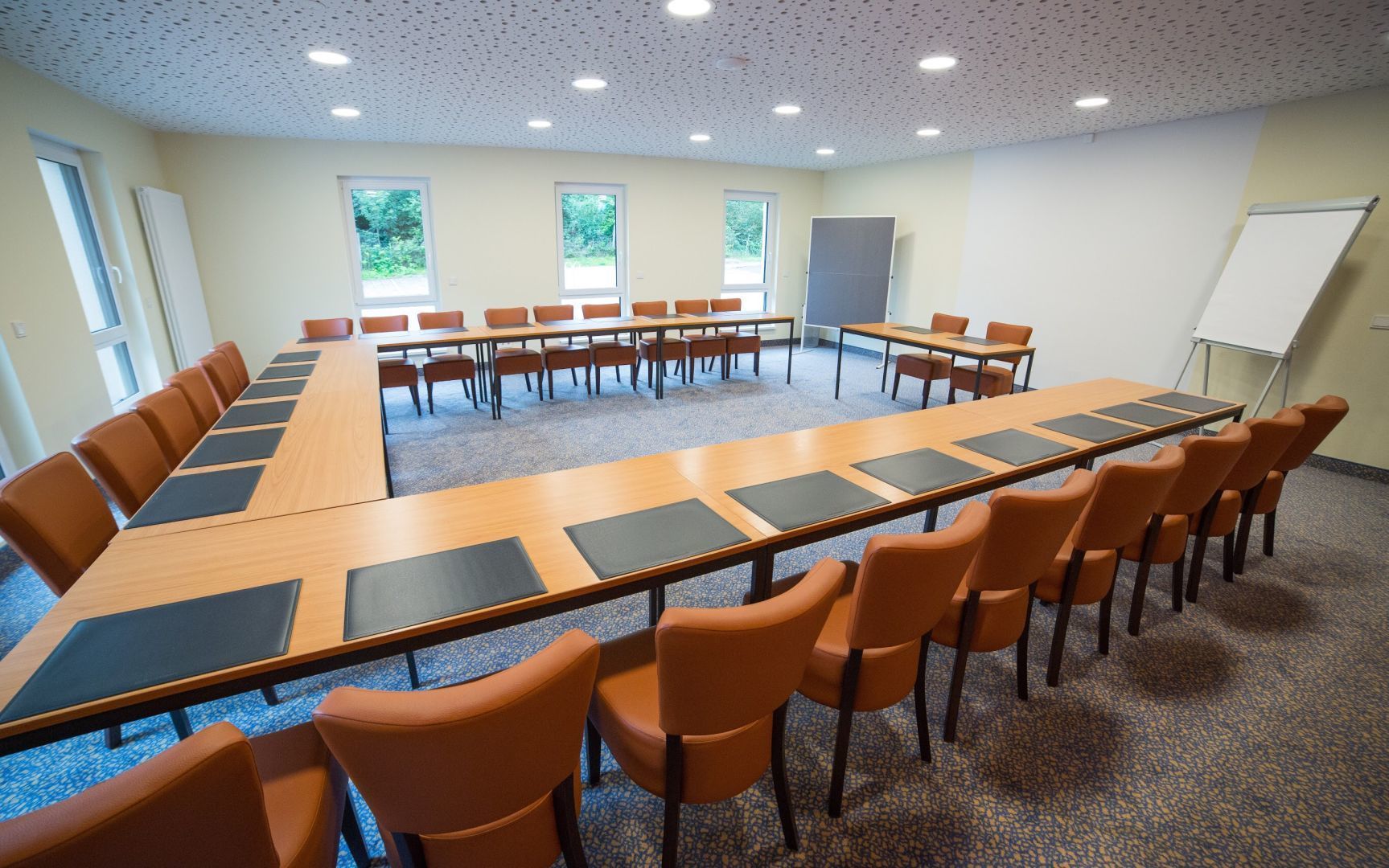 Une salle de conférence avec une longue table, des chaises orange et un tableau blanc.