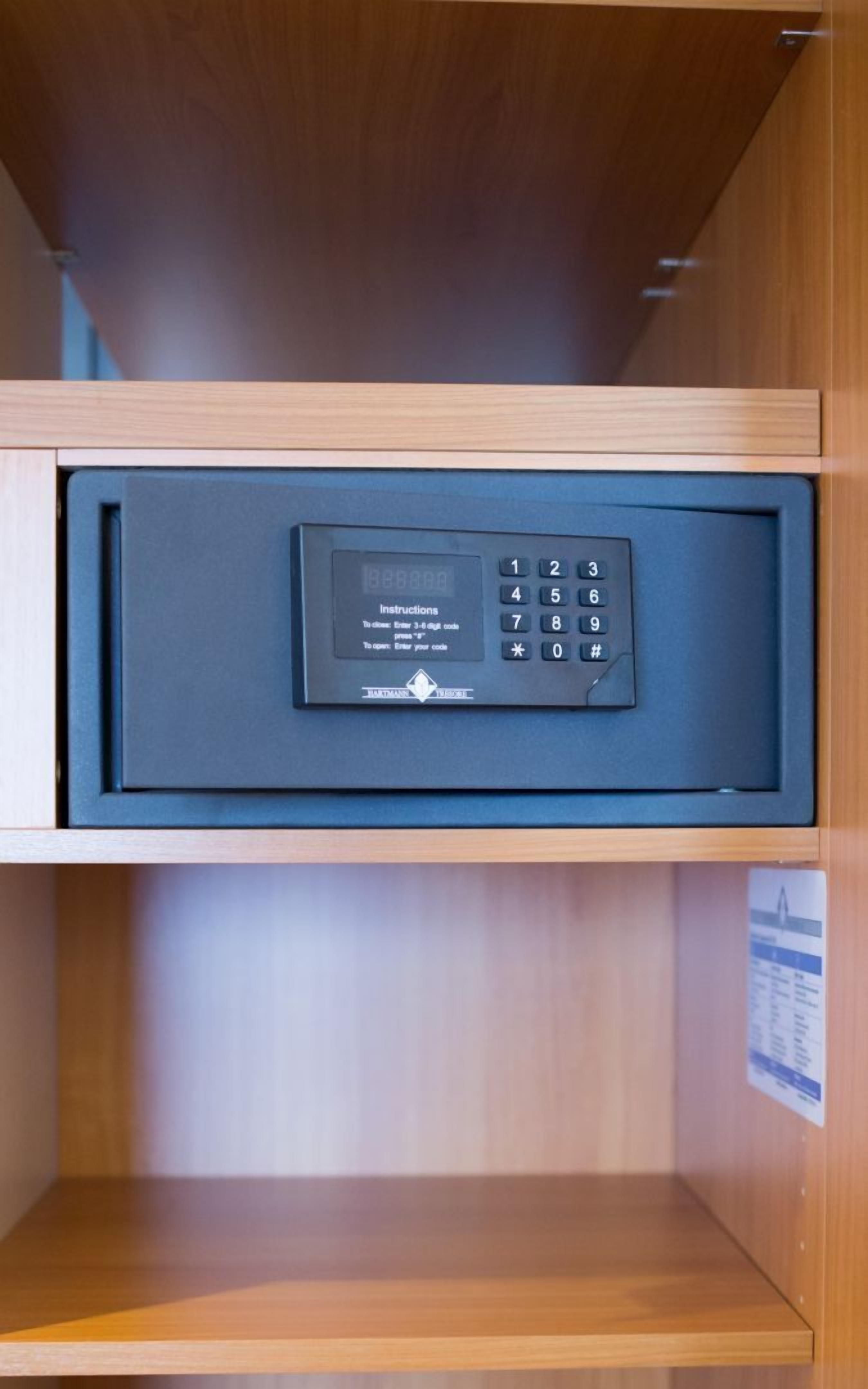 Un appareil électronique noir, doté d’un clavier et accompagné d’un mode d’emploi, est posé sur une étagère en bois.
