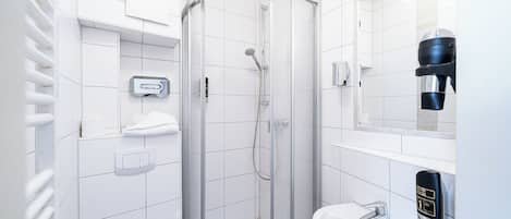 A modern bathroom with a glass-enclosed shower, a white sink, and a hand soap dispenser.