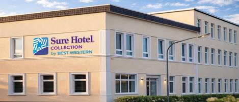 A hotel building with a sign reading 'Sure Hotel Collection by BEST WESTERN.'
