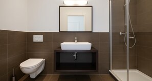 Un baño moderno con inodoro, lavamanos y ducha.