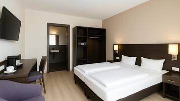 Habitación de hotel con cama, mesitas de noche, un escritorio con silla, televisor y armario.