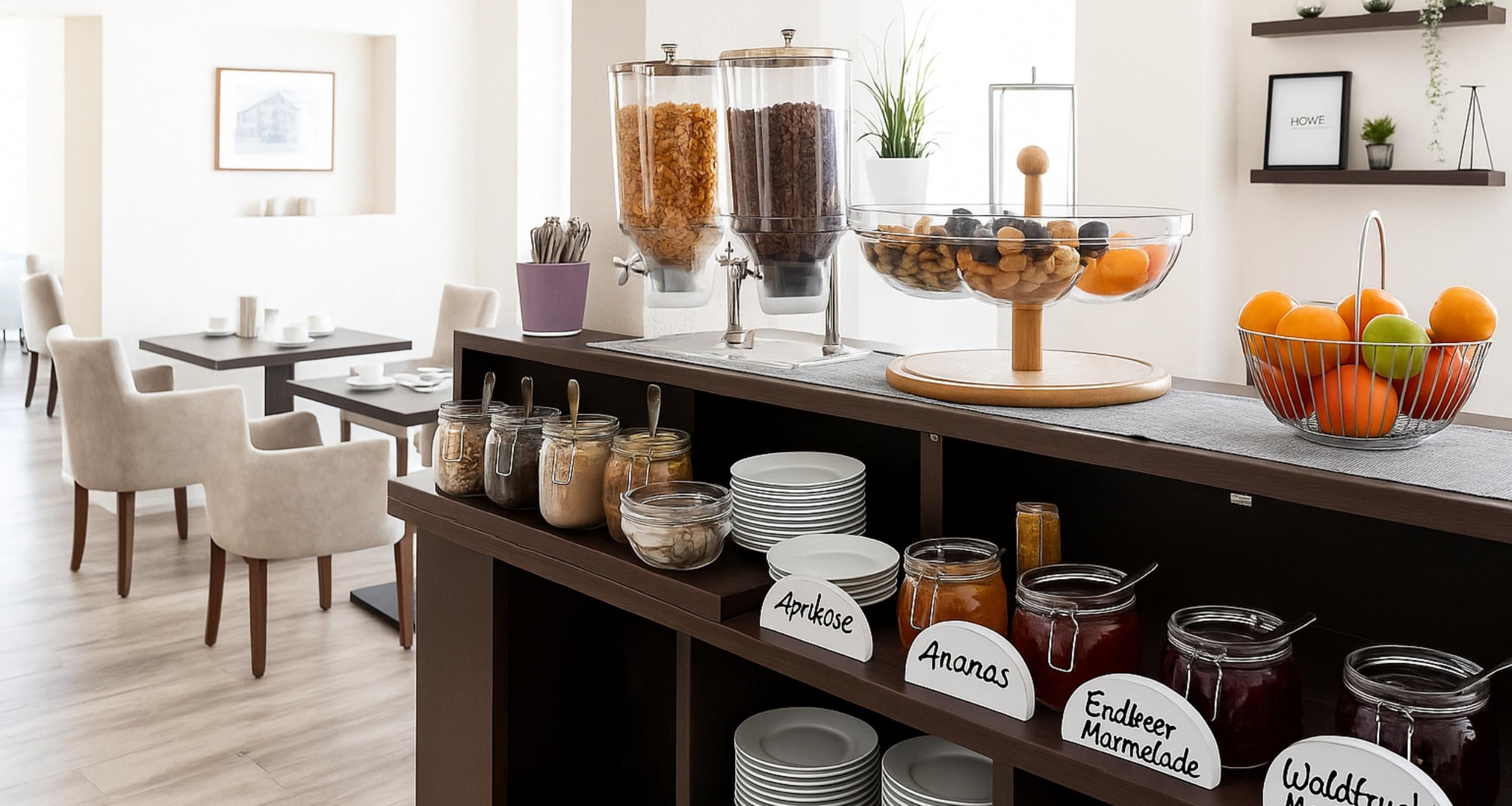 Een buffetgedeelte met bewegwijzerde gerechten, een zithoek en een plant aan de muur.