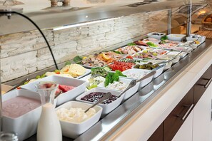 Un buffet proposant une variété de plats, notamment des viandes, des fromages et des salades.