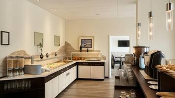 A modern kitchen with a buffet setup, including a counter with food items and a dining area with chairs and a table.