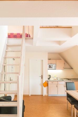 A compact kitchen with a microwave, sink, and a small dining area with a table and chairs. - Ostseehotel Rike (Zierow)