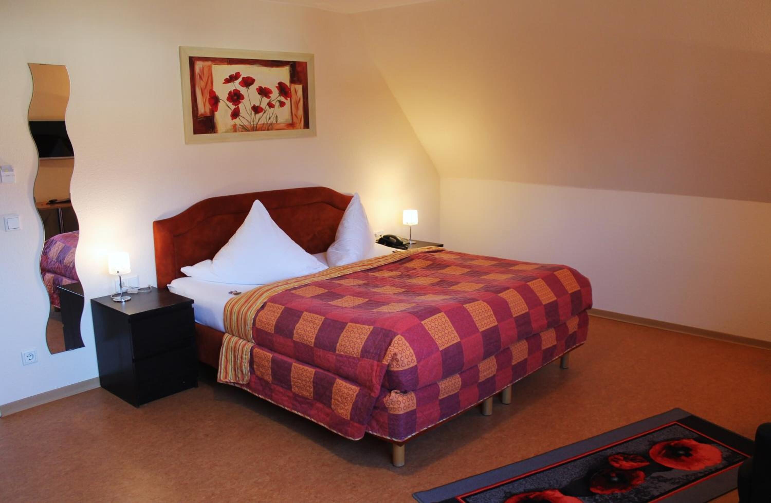 Une chambre à coucher avec un lit, une table de chevet, une lampe et un tableau au mur.