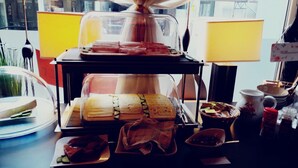 Un espositore con panini e condimenti, una macchina del caffè e vista dalla finestra.