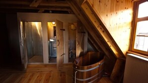 A wooden interior with a wooden bathtub, a radiator, and a window.