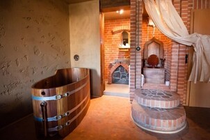 Un baño rústico con una bañera de madera, una chimenea de piedra y una pared de ladrillo.