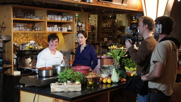 A kitchen with a coffee machine, pots, and a variety of fresh produce on the counter.