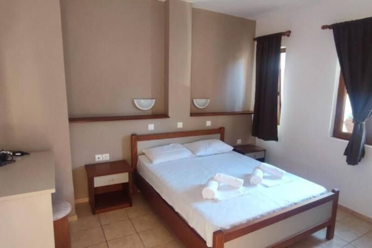 A bedroom with a bed, bedside tables, a mirror, and a window with curtains.